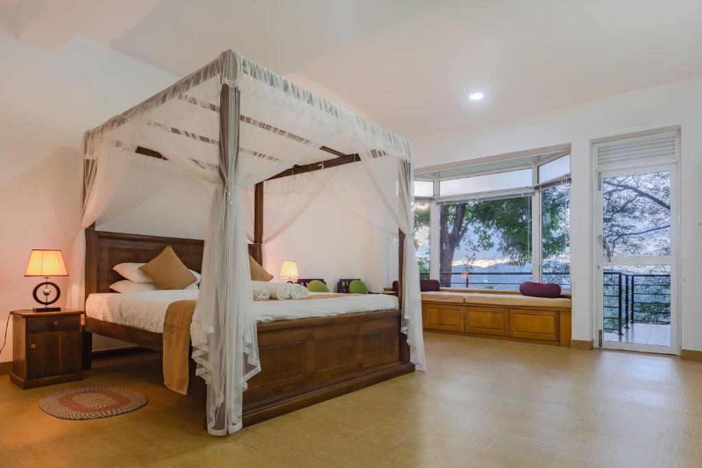 a bedroom with a canopy bed and a large window at Villa Mount Melody in Kandy