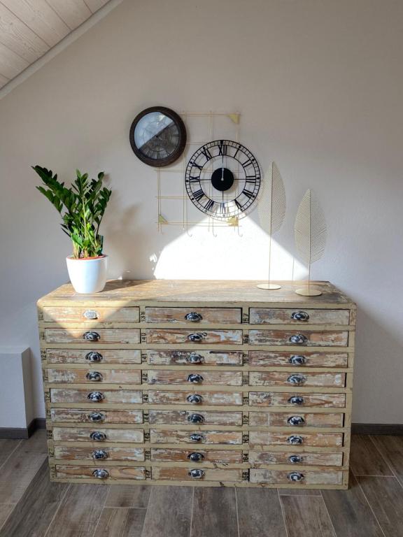 a wooden dresser with a clock and a plant on it at Holiday Deluxe Apartment in Travers