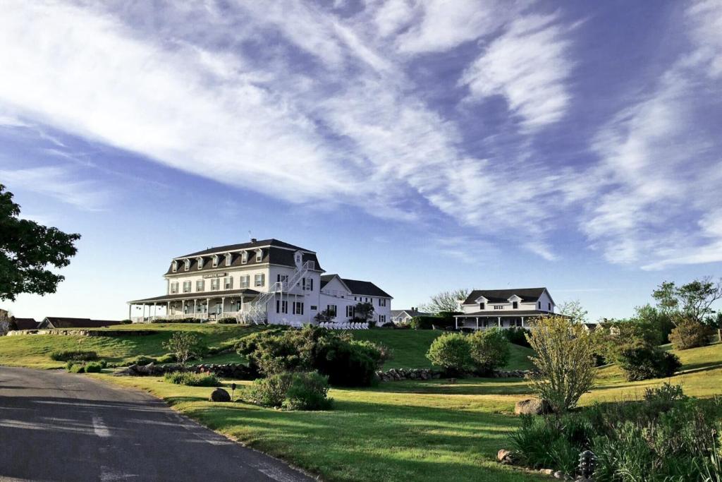duży biały dom na wzgórzu z drogą w obiekcie Atlantic Inn w New Shoreham