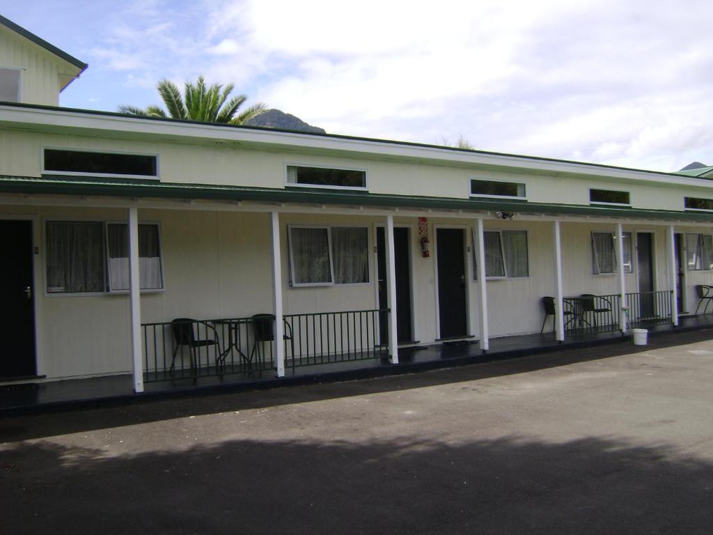 an old white building with chairs on the porch at Mataki Motel in Murchison