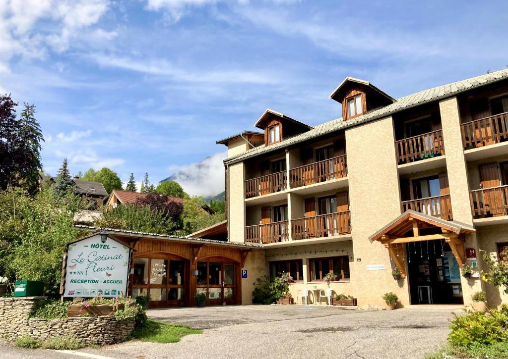 un grand bâtiment avec un panneau devant lui dans l'établissement Le Catinat Fleuri, à Guillestre