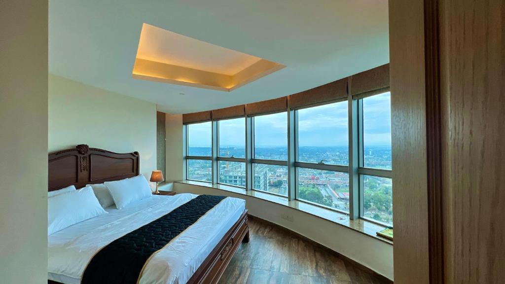 ein Schlafzimmer mit einem großen Bett und großen Fenstern in der Unterkunft Centaurus Apartment in Islamabad