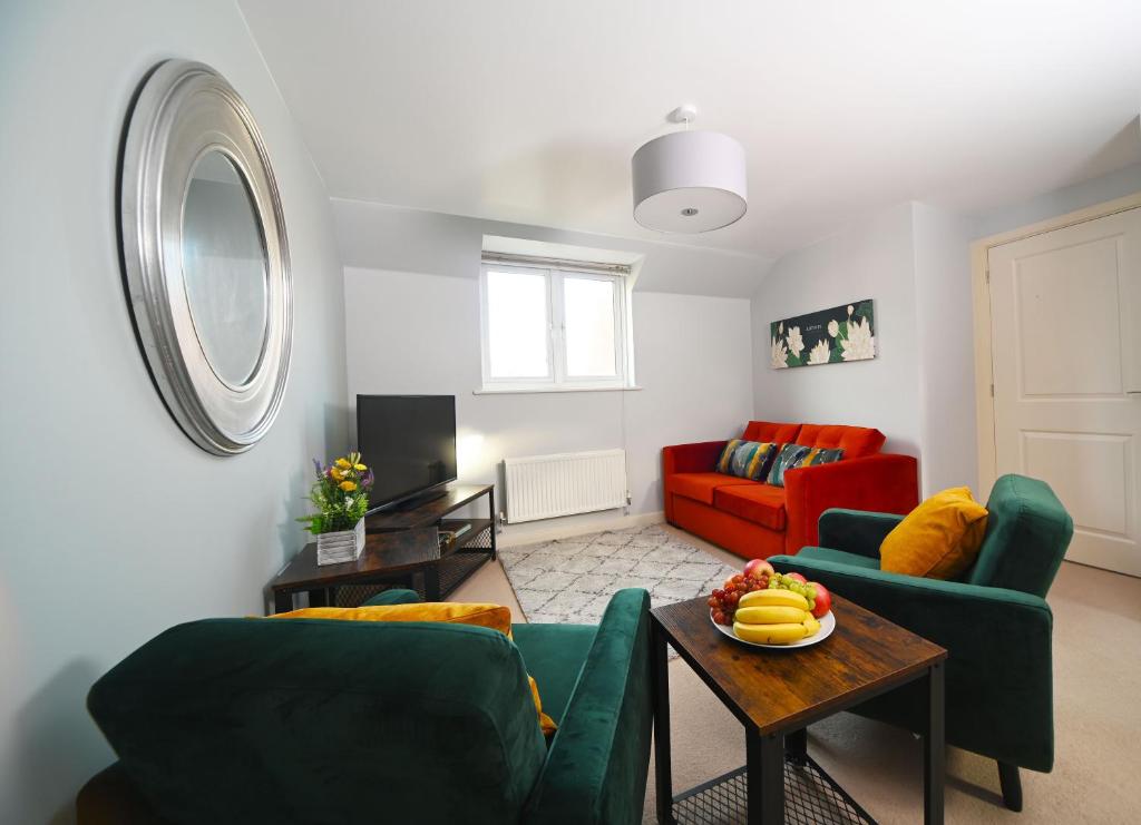 a living room with two green couches and a table at Ideal Coach House in Swindon