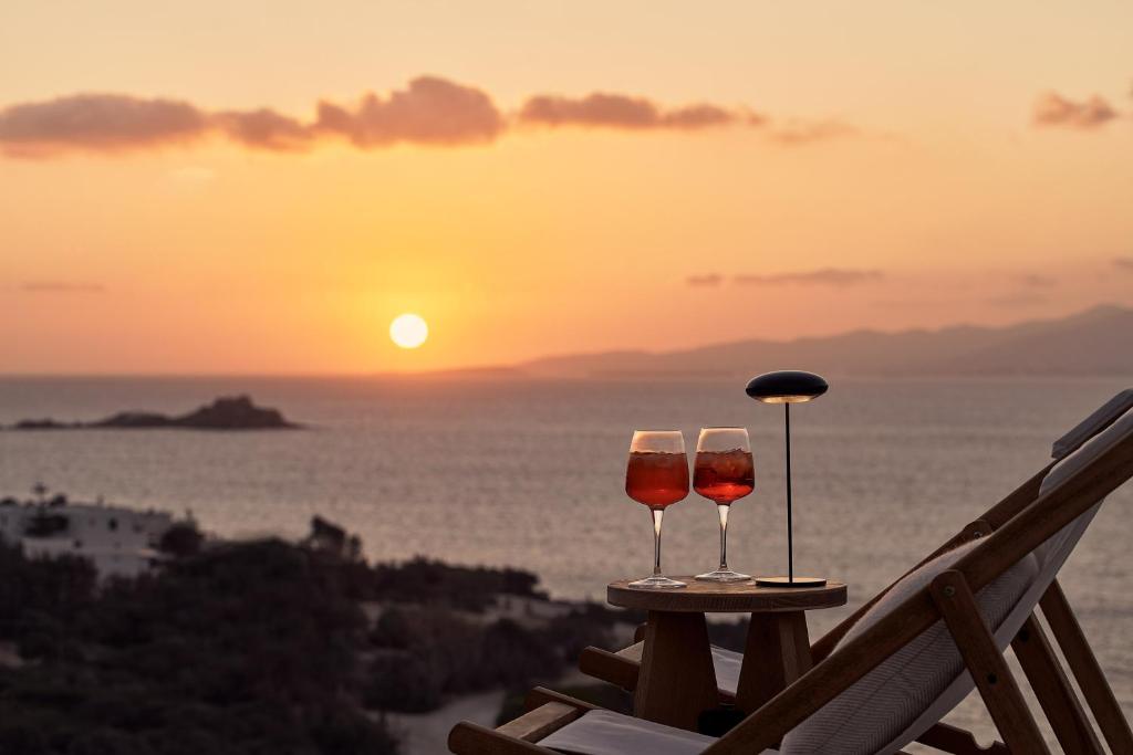 two glasses of wine sitting on a table with the sunset at Naxea Villas I in Plaka