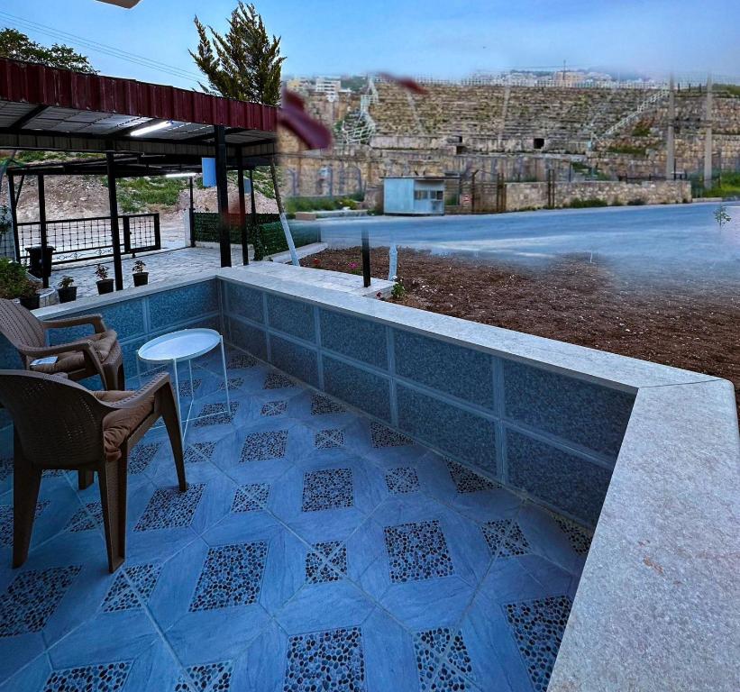 un patio de azulejos azules con mesa y sillas en Panorama Jerash HOTEL (2), en Jerash