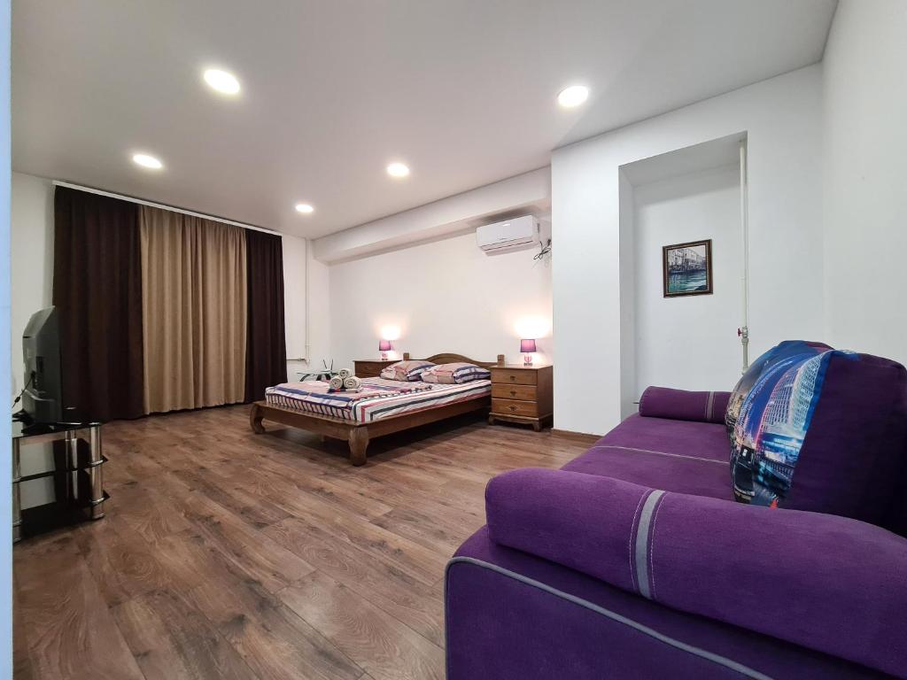 2-room Luxury Apartment on Sobornyi Avenue 192, by GrandHome في زاباروجيا: غرفة معيشة مع أريكة أرجوانية وسرير