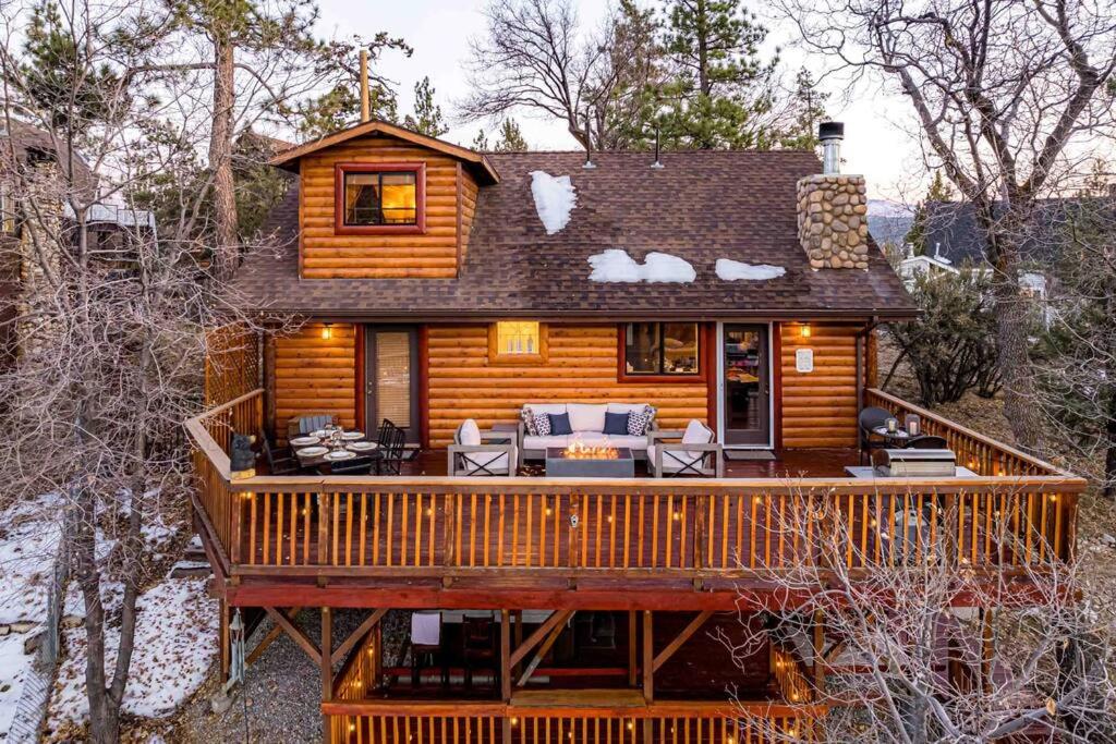 uma cabana de madeira com um deque na floresta em Luxury cabin, hot tub, slopes, lake & VIEWS! em Fawnskin