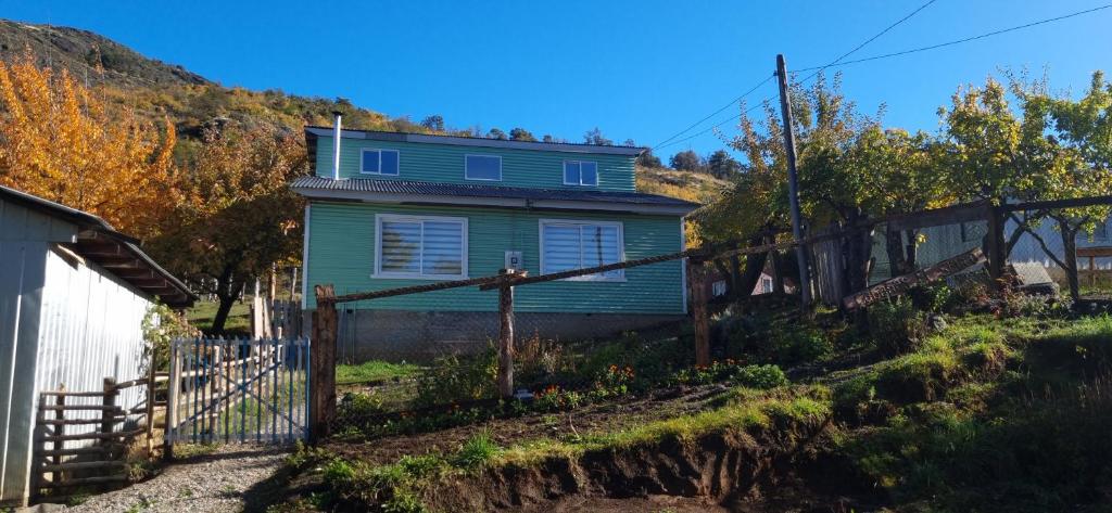 a blue house with a fence in front of it at Cabaña el Sauco in Puerto Guadal