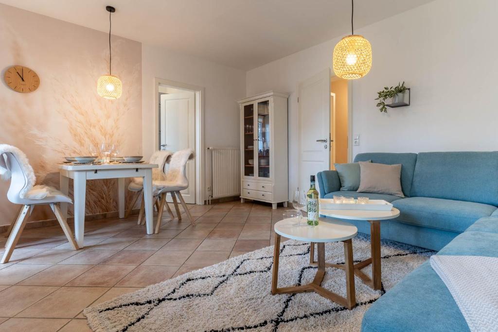 uma sala de estar com um sofá azul e uma mesa em Koje 34 em Sankt Peter-Ording