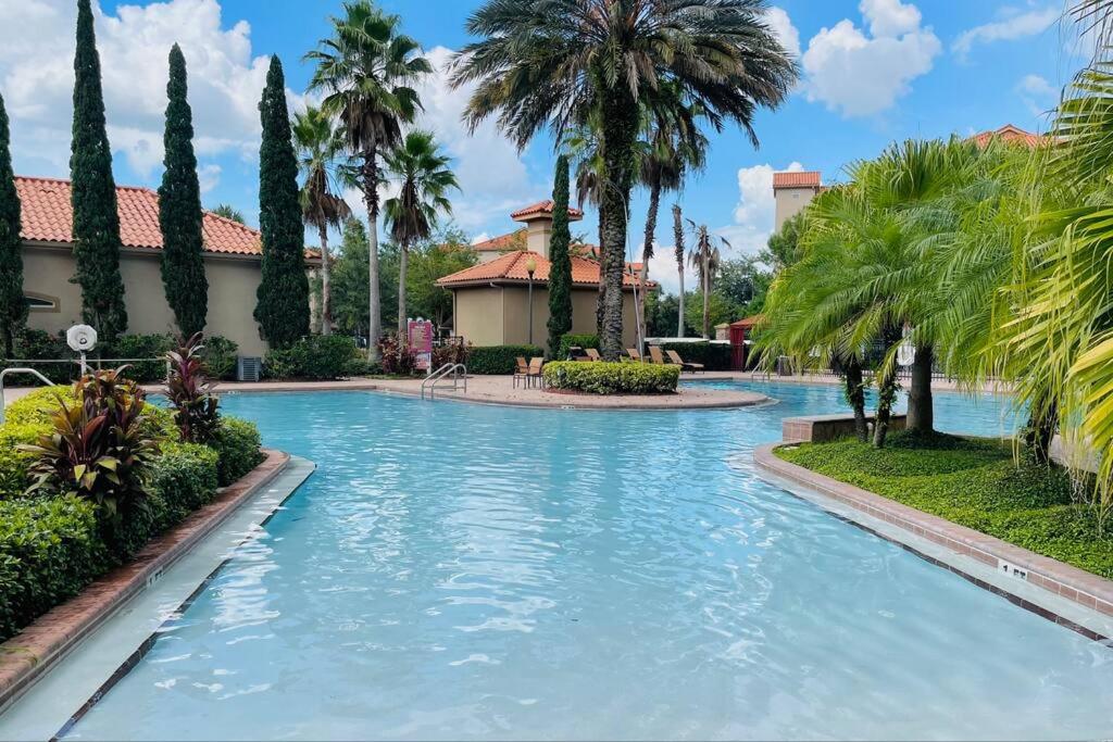 una piscina en un complejo con palmeras en Apartment 3 BR in Tuscana Resort , 15" from Disney en Kissimmee