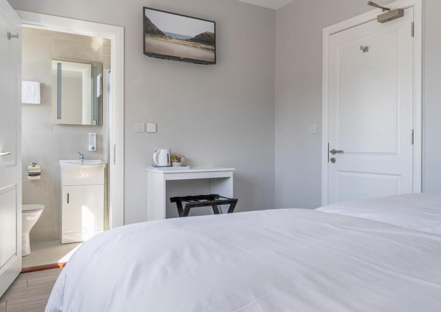 a white bedroom with a white bed and a bathroom at The Doneraile Room 2 in Waterford