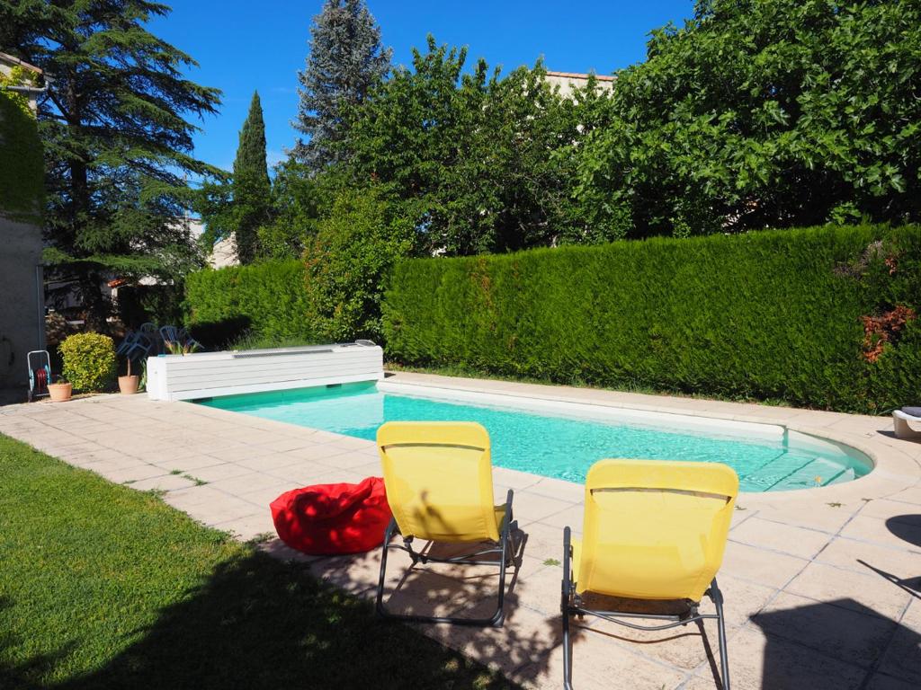 two yellow chairs sitting next to a swimming pool at Appartement en Provence-Lubéron - piscine et calme in Volx