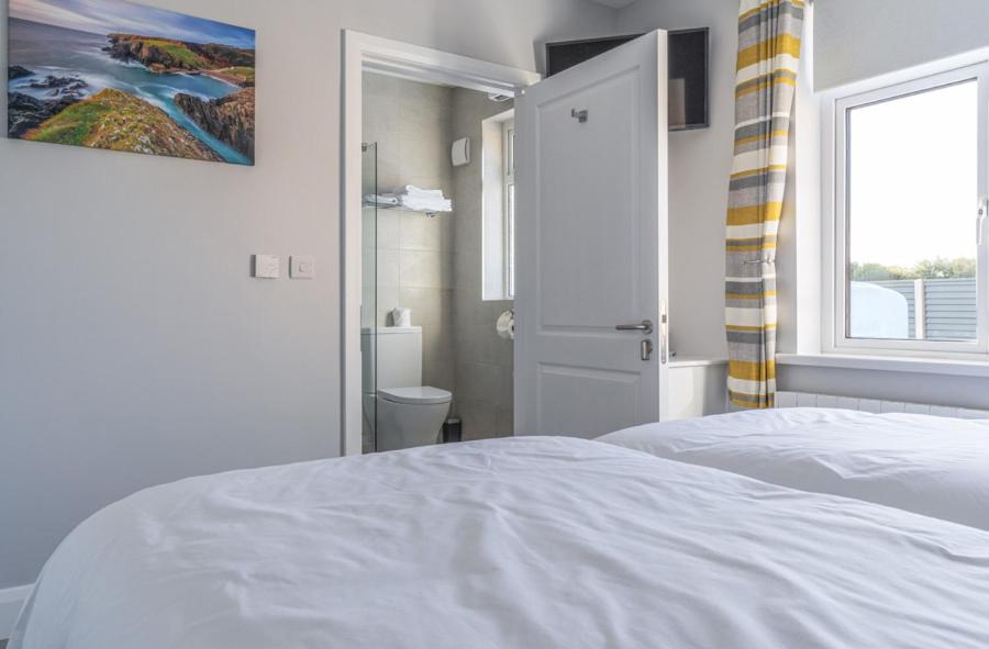 a white bedroom with a bed and a window at Newtown Cove Room 1 in Waterford