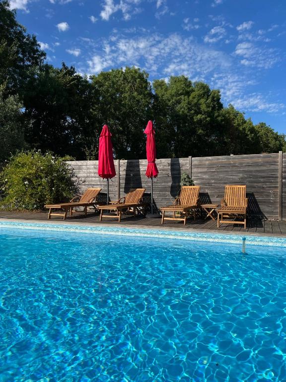 - une piscine avec deux parasols et des chaises à côté dans l'établissement La laiterie, à Bouhet