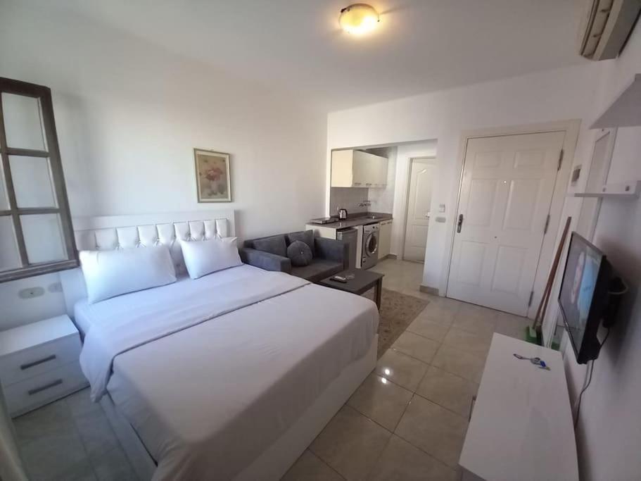sypialnia z dużym białym łóżkiem i telewizorem w obiekcie Studio Delta sharm Resort w Szarm el-Szejk