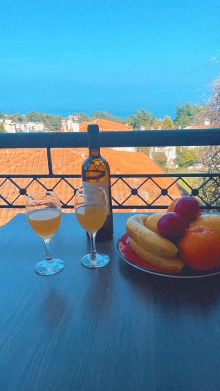 a table with a plate of fruit and two glasses of wine at Klapidis apartments in Kriopigi