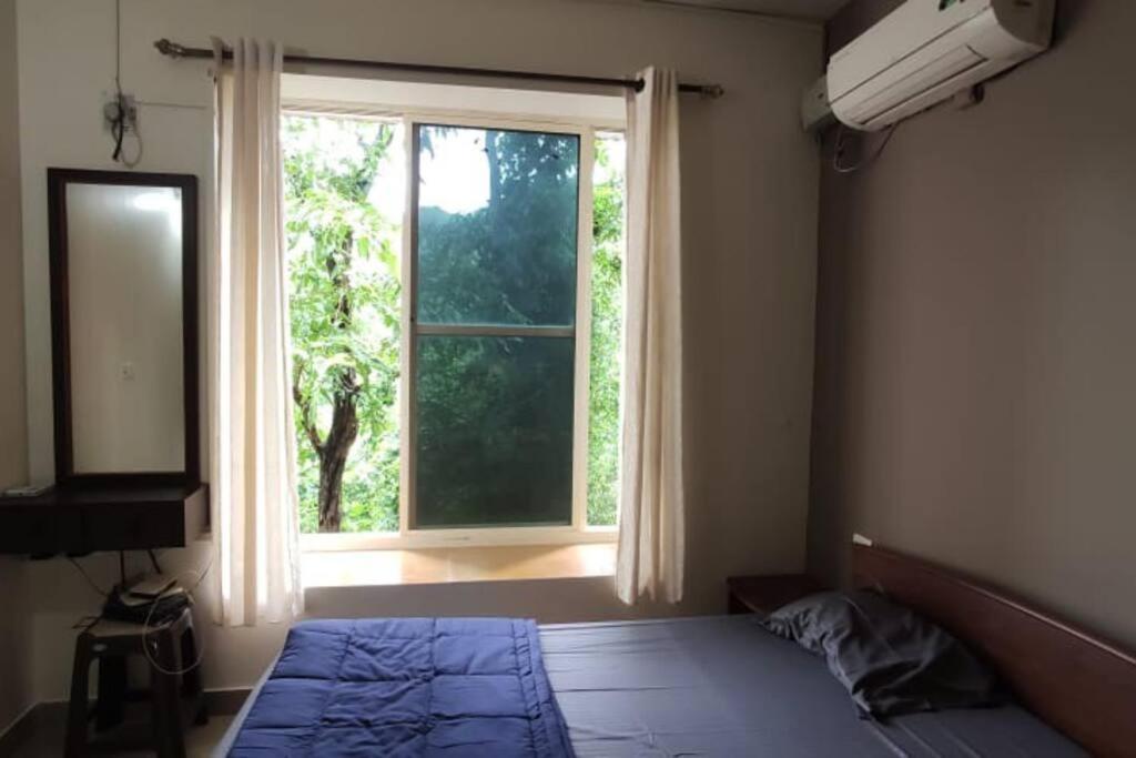 a bedroom with a bed and a large window at Furnished Apt near Palolem Beach¶WiFi ¶Forest view in Canacona