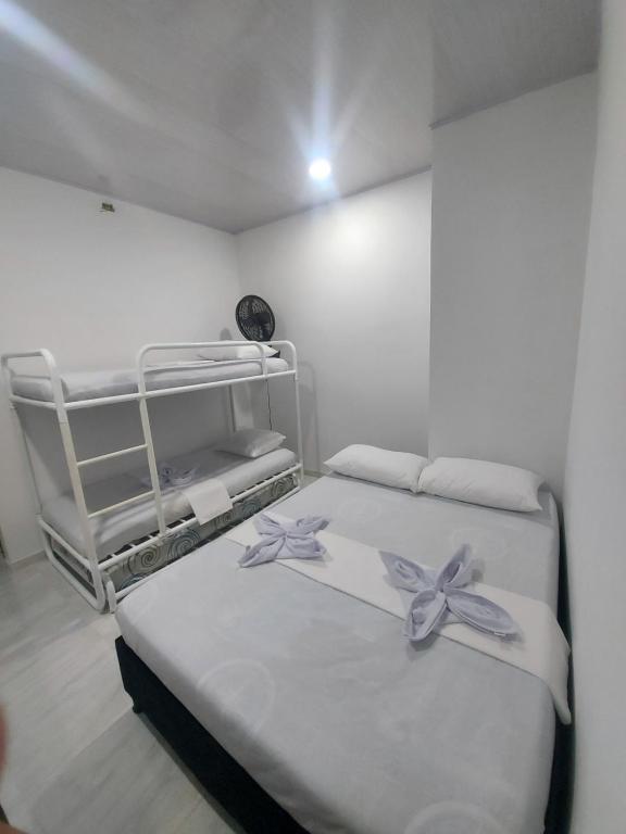 Dos camas en una habitación blanca con flores. en HOTEL HAUSE San Antero Córdoba, en San Antero