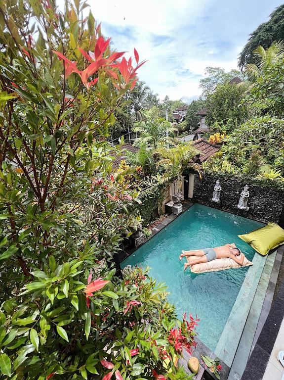 a woman laying in a swimming pool at a resort at Dharma Shanti Villa - Private Pool - Peaceful Ubud Escape in Ubud