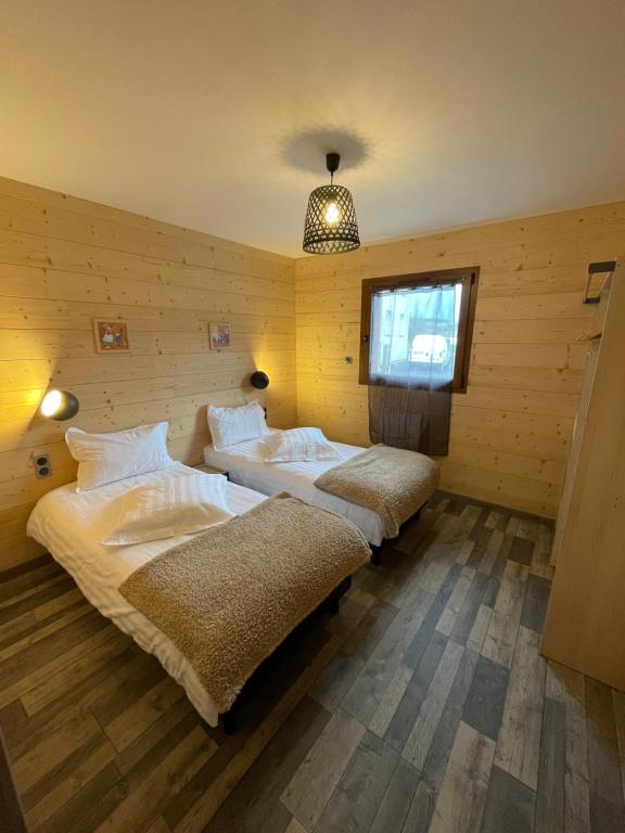 two beds in a room with wooden walls at Le Chalet Du Castor in Anould