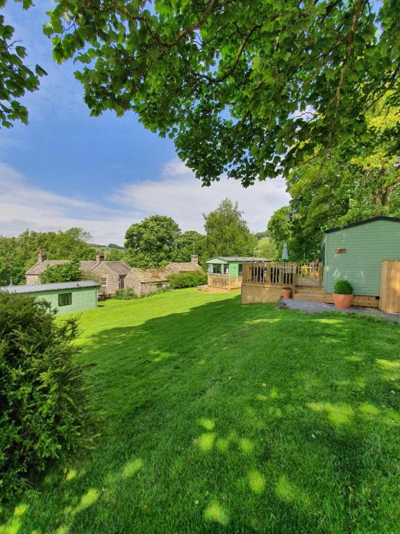 a yard with a green lawn with a fence and a green house at Howgill farm Bolton Abbey in Appletreewick