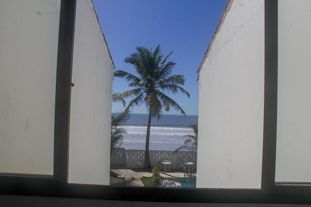 a view of the beach from a window with surfboards at Pousada Solar das Flores in Conceição da Barra