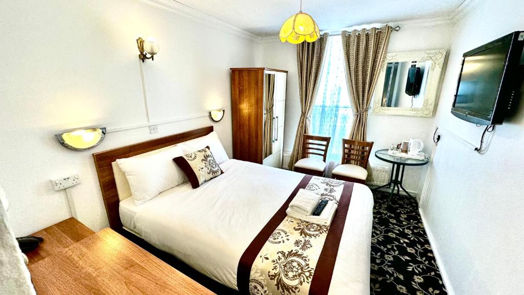 a bedroom with a bed and a tv and a table at Andorra Guest Accommodation in Brighton & Hove