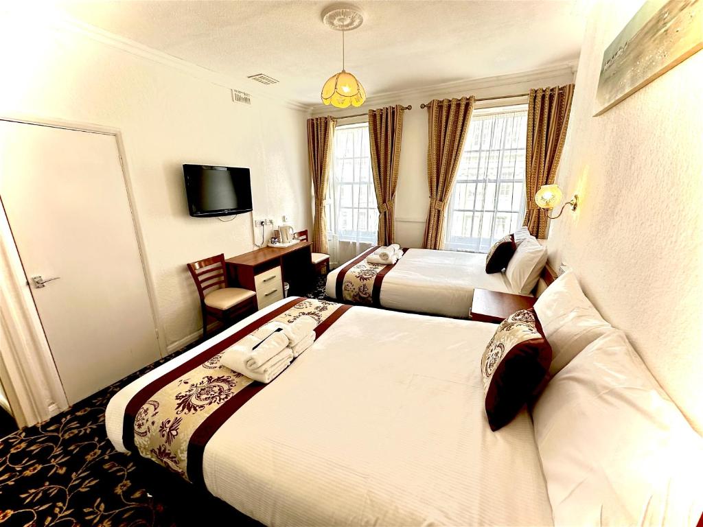 a hotel room with two beds and a television at Andorra Guest Accommodation in Brighton & Hove
