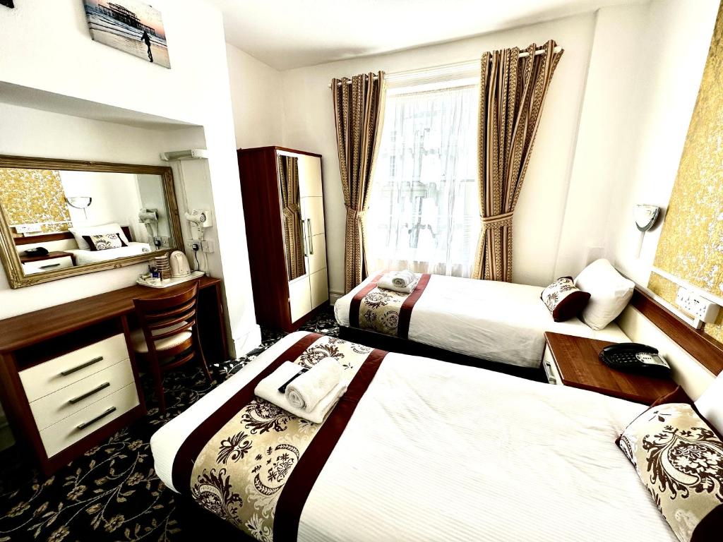 a hotel room with two beds and a mirror at Andorra Guest Accommodation in Brighton & Hove
