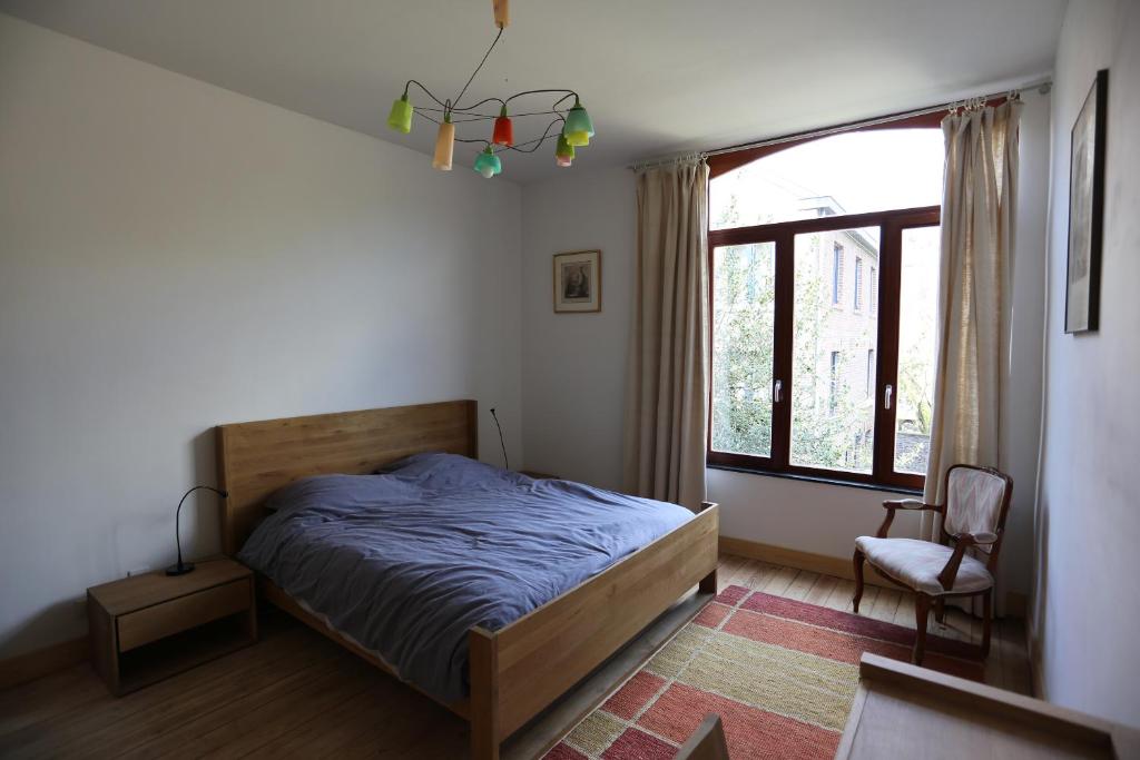 a bedroom with a bed and a window and a chair at Bed and breakfast Le fourchu fossé in Liège
