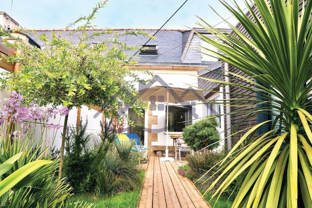 a garden with a wooden walkway in front of a house at LocaLise - M20 - La maison des Dunes à 2 pas du centre - Tout à pied, plage, port, centre, commerces marché - Wifi inclus - Linge de lit inclus - Animaux bienvenus in Le Guilvinec