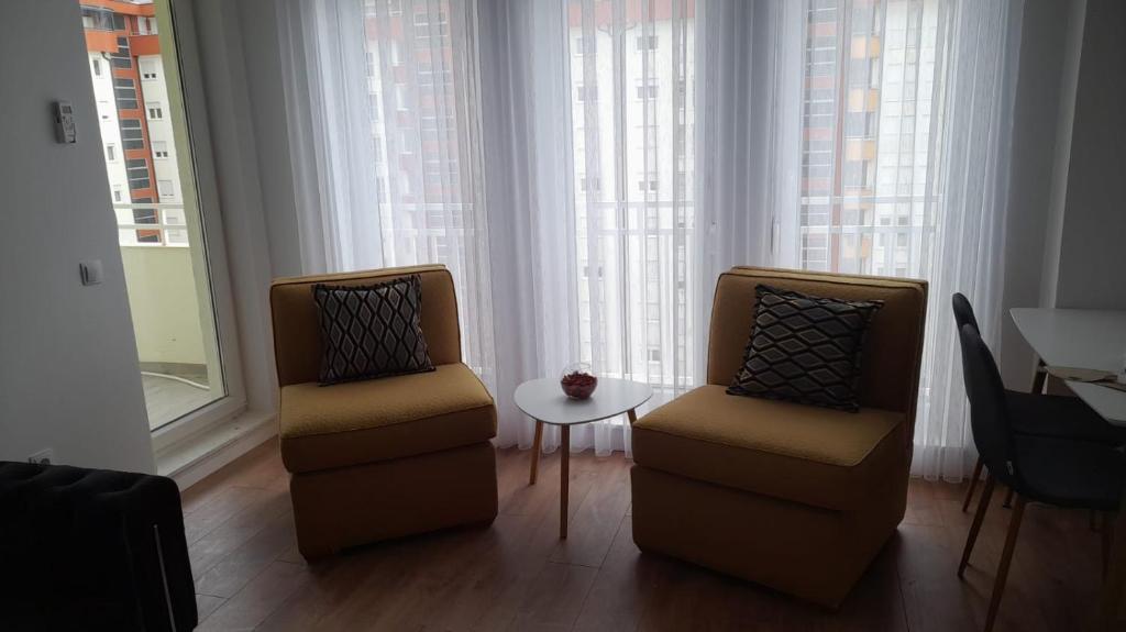 two chairs and a table in a room with windows at Street C apartment nr 2 in Pristina