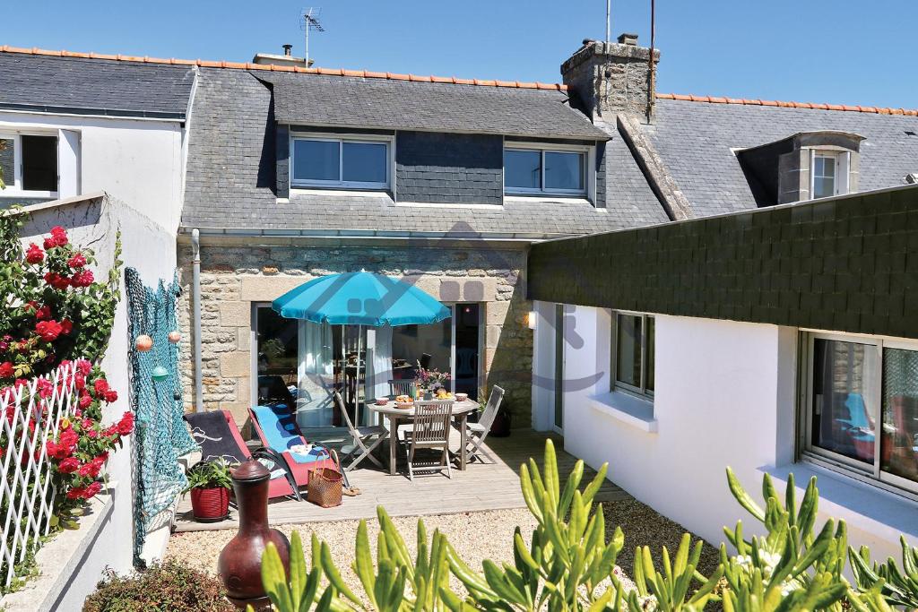 une terrasse avec une table et un parasol bleu dans l'établissement LocaLise - M3A La Maison du pêcheur au Guilvinec - Chambres vue mer - A 20m de la mer située à la pointe de Men Meur - Tout à pied, plage, port, centre, commerces, marché - Wifi inclus - Linge de lit inclus - Jardin clos - En option , ménage et serviettes, au Guilvinec