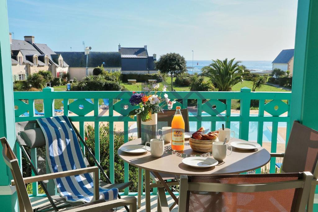 una mesa en un balcón con vistas al océano en LocaLise au Guilvinec - A15 - Vue sur la mer la piscine et le jardin - Tout à pied, plages, port, centre, commerces, marché - Wifi inclus - Animaux bienvenus - Linge de lit inclus, en Le Guilvinec