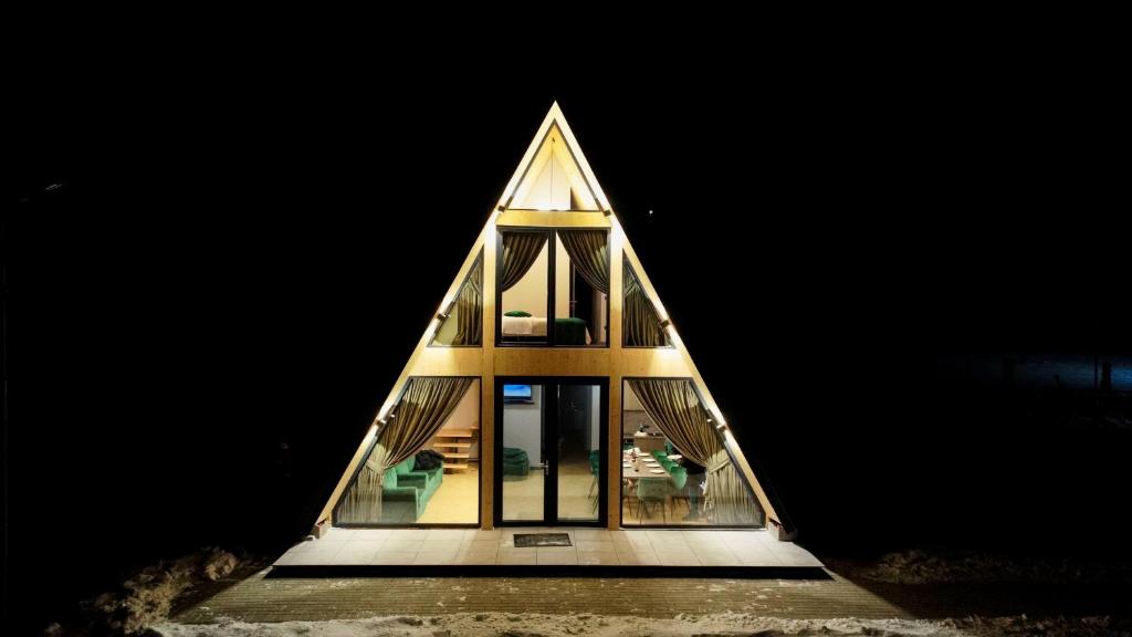 a pyramid shaped house is lit up at night at CABANA 7 CRESTE in Borşa