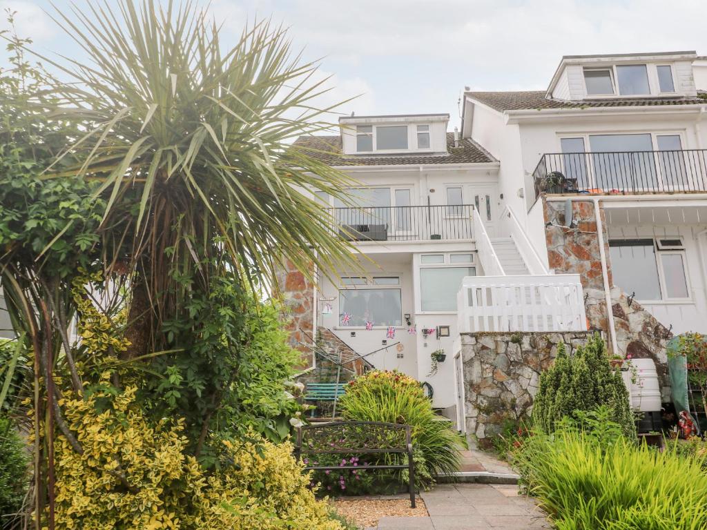 a white house with a palm tree in front of it at Flat 6 in Falmouth