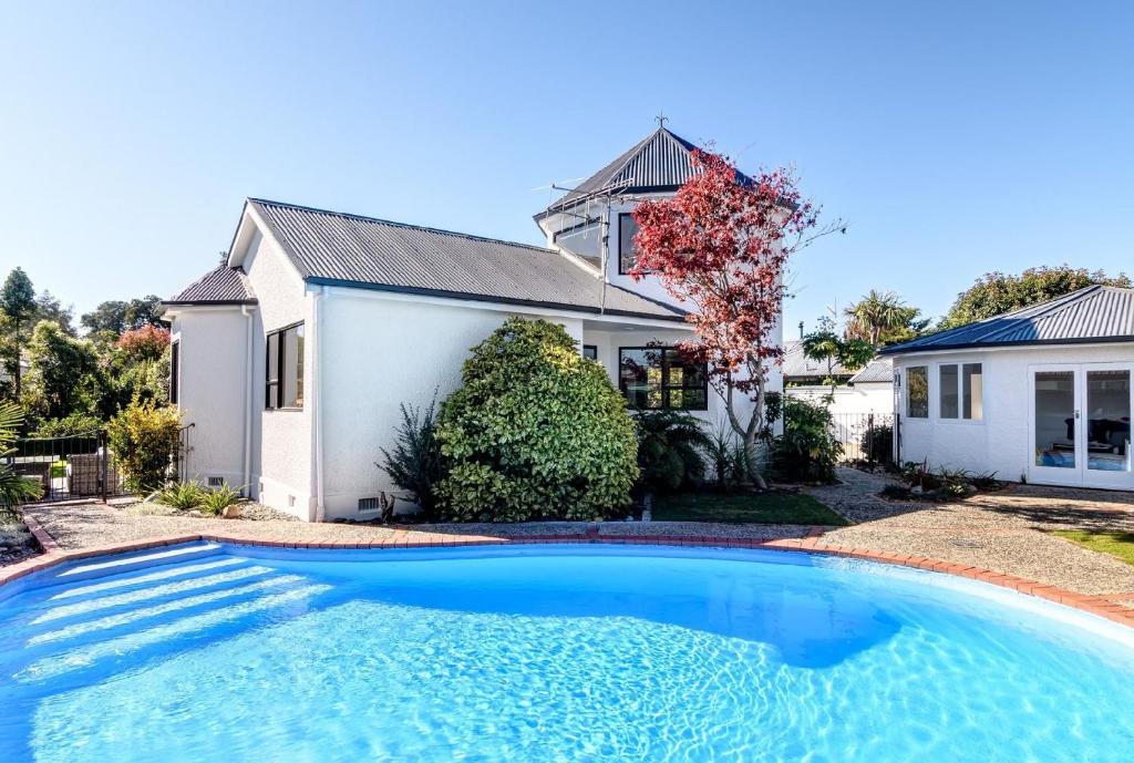 a house with a swimming pool in front of a house at The Pool House - King Deluxe Studio in Motueka