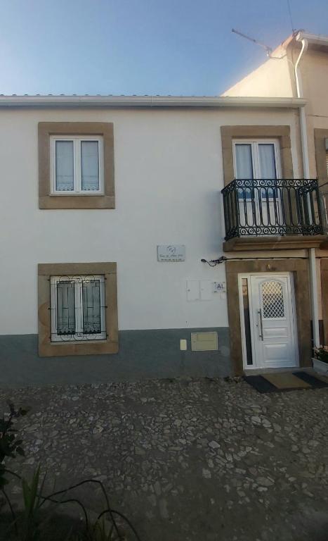 a white house with a balcony and a door at Casa da Aldeia 2021 in Escalhão