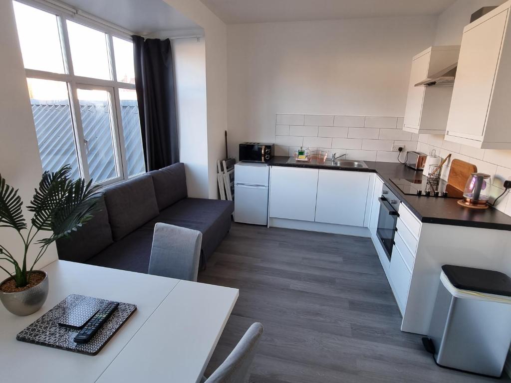 een keuken en een woonkamer met een tafel en een bank bij Granada Apartments Queen's Promenade in Blackpool