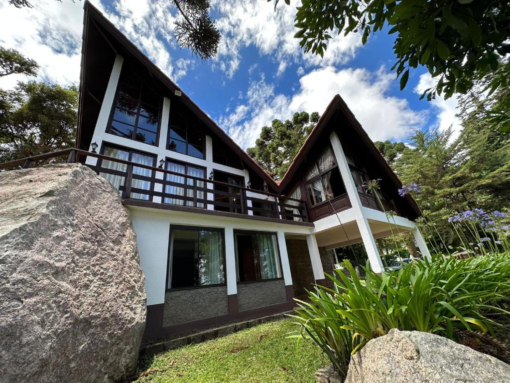une maison avec un grand rocher en face dans l'établissement Casa das Pedras, à Monte Verde