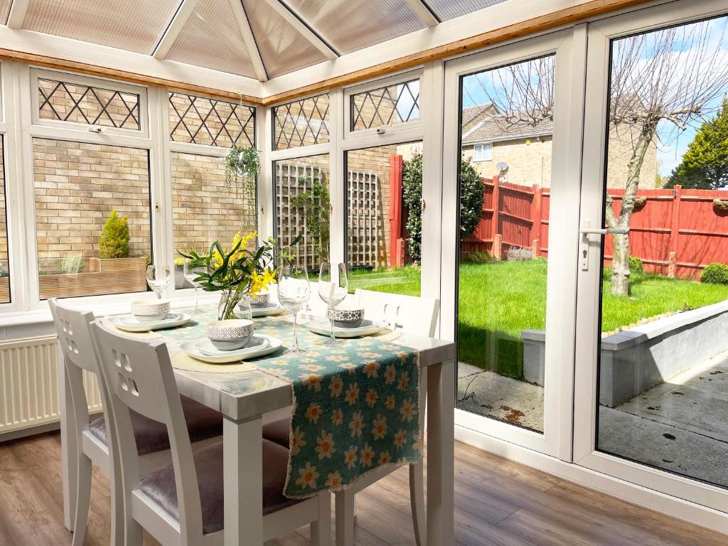 a conservatory dining room with a table and chairs at Bright, Airy & Beautifully Decorated 3 Bedroom Home in Kettering