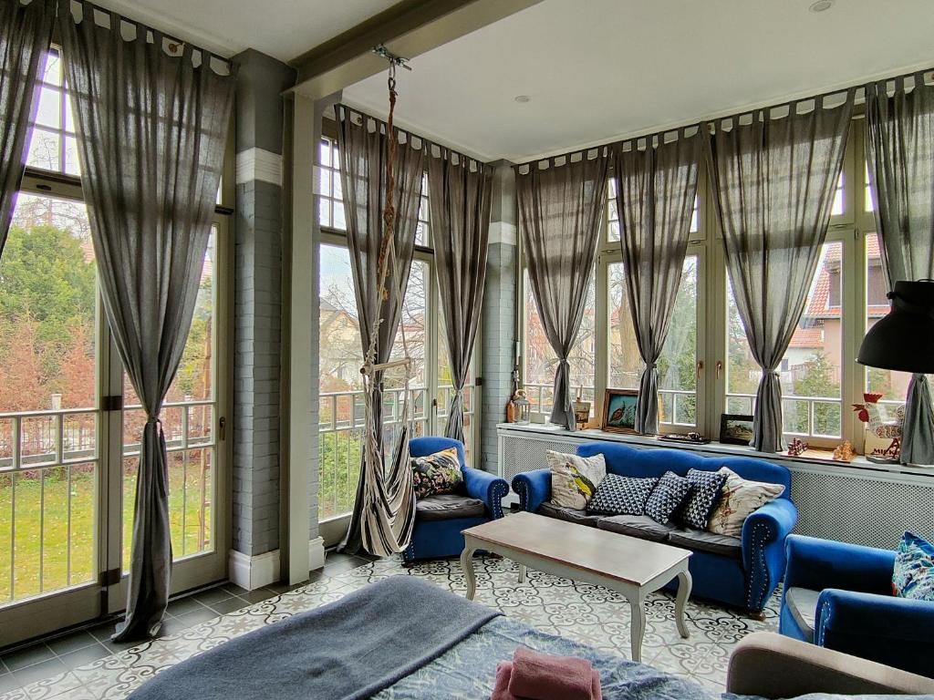 Elle comprend un salon doté d'un mobilier bleu et de grandes fenêtres. dans l'établissement Villa Ley, à Jelenia Góra