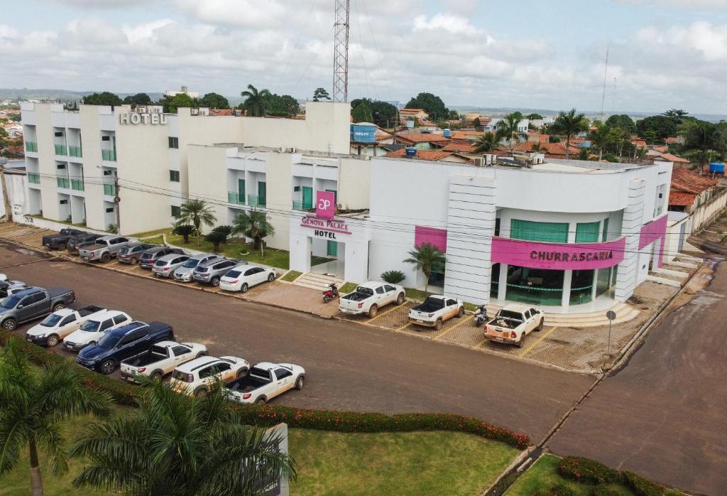 un gran edificio blanco con coches aparcados en un aparcamiento en Gênova Palace Hotel, en Acailandia