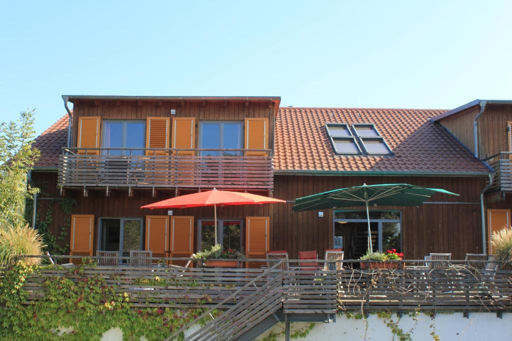 a house with two umbrellas and tables and chairs at Johanneshof Gästehaus in Hockenheim