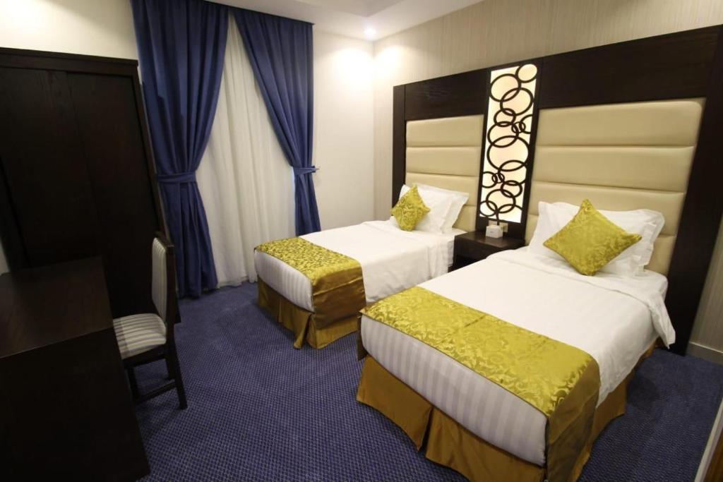 um quarto de hotel com duas camas e uma cadeira em السهم الذهبي للشقق المخدومة em Taif