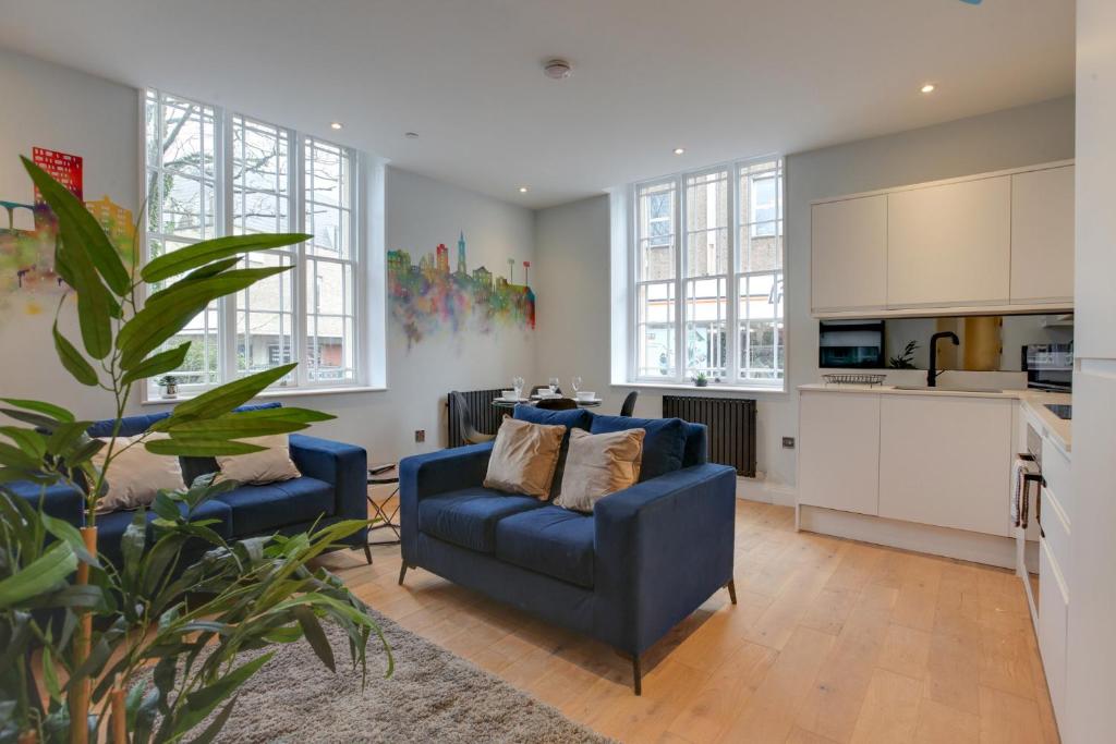 een woonkamer met twee blauwe banken en een keuken bij New London Life Executive Apartments in Chelmsford