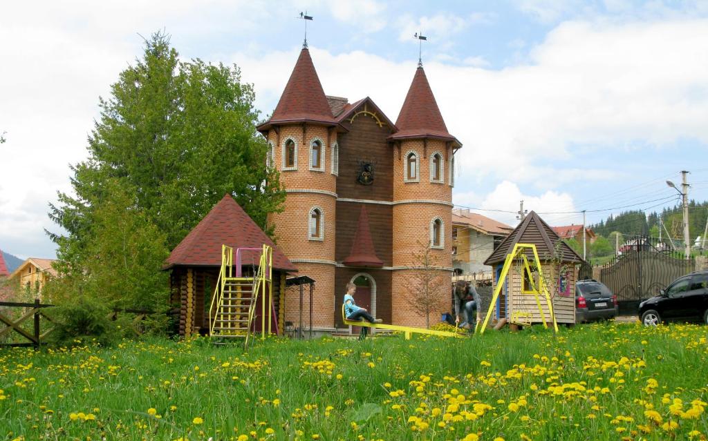 un bâtiment avec une tour et une aire de jeux dans un champ dans l'établissement Castle Belvedere, à Bukovel