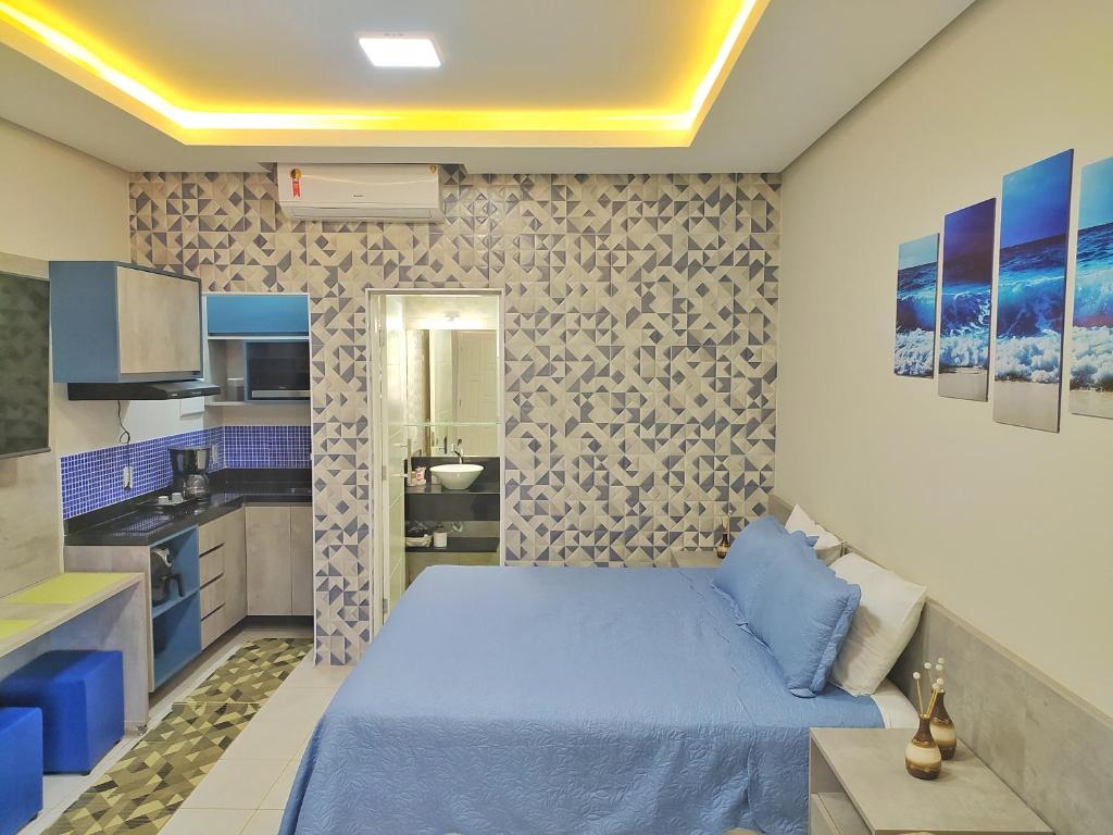 a bedroom with a blue bed and a kitchen at Riviera Flat in Bertioga