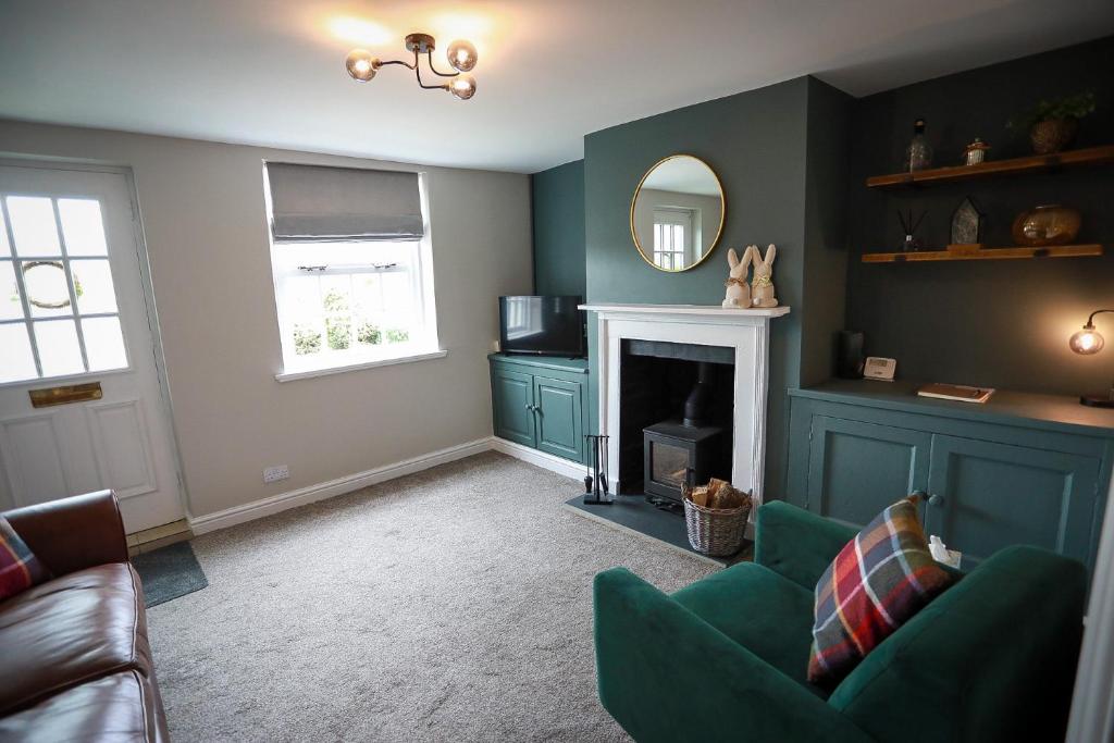 a living room with a green couch and a fireplace at Auctioneers Cottage in Louth