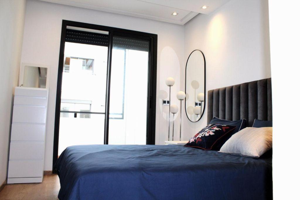 - une chambre avec un lit bleu et une grande fenêtre dans l'établissement ANOUAL PLAZZA - 2 BEDROOMS APPARTMENT, à Casablanca